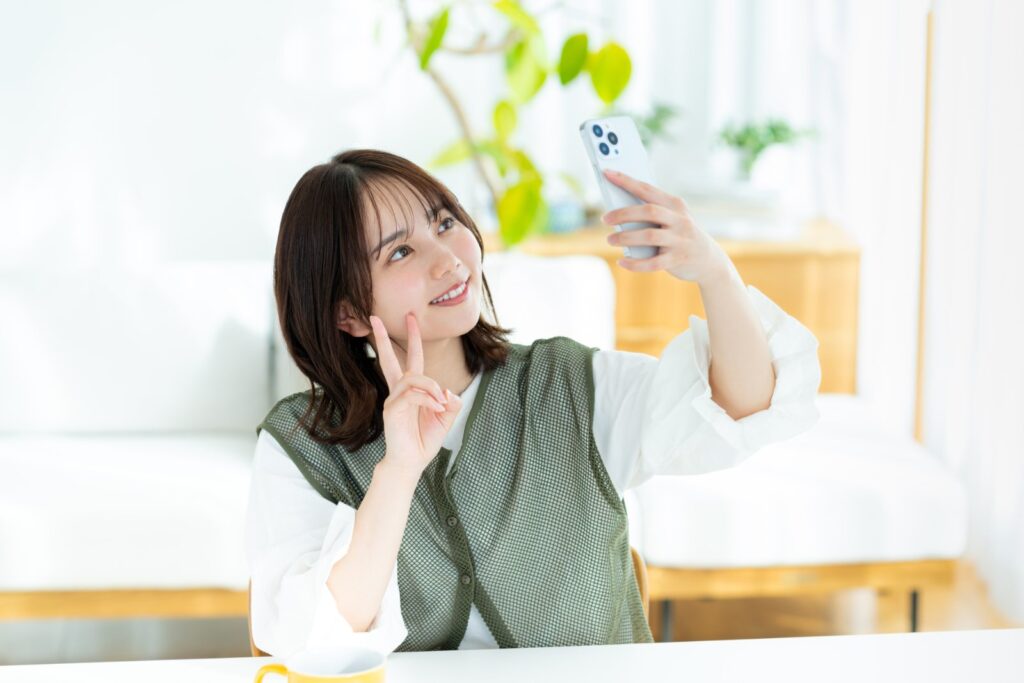 部屋でスマートフォンを操作する女性