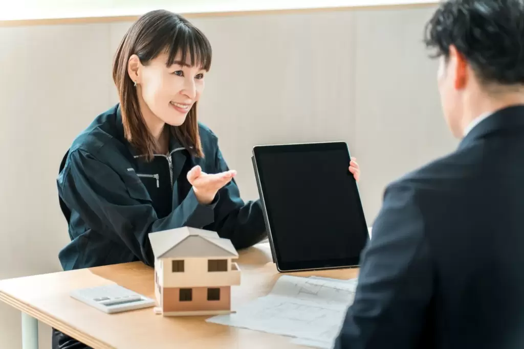タブレットで提案する作業着姿のスタッフ